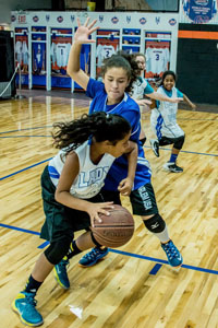 Girls playing basketball on indoor court at Artistic Stitch Sports Complex Queens, New York.